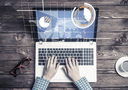 Top view of woman in checked shirt sitting at wooden table with laptopの写真素材