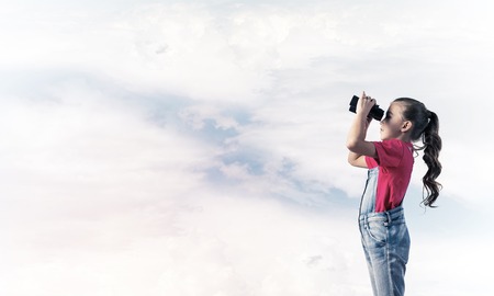 Little cute girl in overalls against sky background dreaming about futureの写真素材