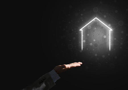 Businessman hand presenting glowing home icon or symbolの写真素材