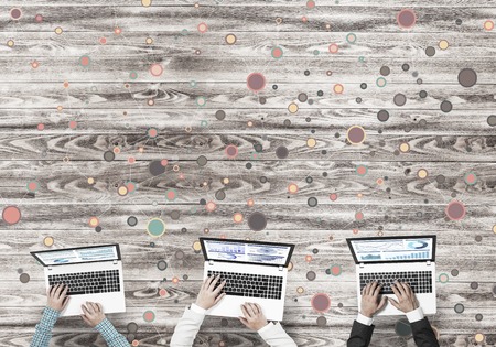 Group of three people with devices in hands working together as symbol of networking and communicationの写真素材