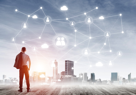 Back view of businessman looking at modern cityscape and connection conceptの写真素材
