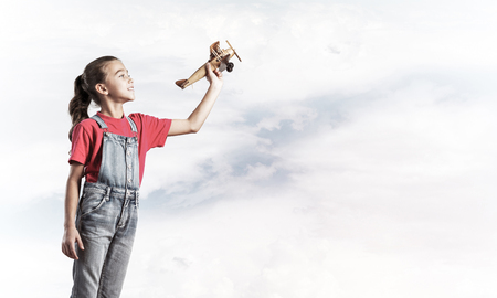 Cute kid girl in overalss with retro plane model in handの写真素材