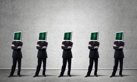 Businessmen in suits with monitors instead of their heads keeping arms crossed while standing in a row in empty room with gray wall on background.の写真素材