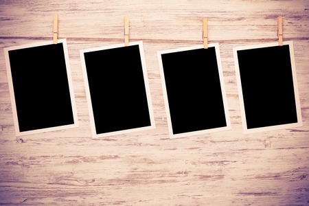 Blank photo frame hanging on rope on wooden textured backgroundの写真素材