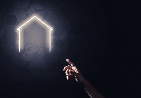 Hand of man touching with finger glowing home icon or symbolの写真素材