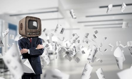 Cropped image of businessman in suit with old TV instead of head keeping arms crossed while standing among flying papers inside office building.の写真素材