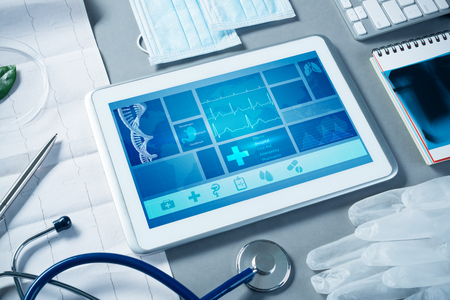 White tablet pc and doctor tools on gray surfaceの写真素材