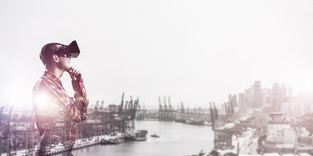 Young man with virtual reality headset or 3d glasses over cityscape backgroundの写真素材