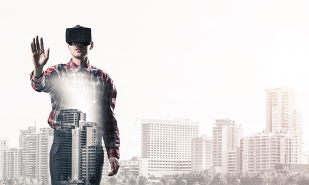 Young man with virtual reality headset or 3d glasses over cityscape backgroundの写真素材