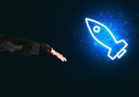 Rocket glowing icon and businessman hand on dark backgroundの写真素材