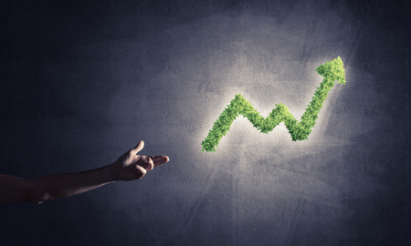 Close of businessman hand and green growing graph as symbol of progress and incomeの写真素材