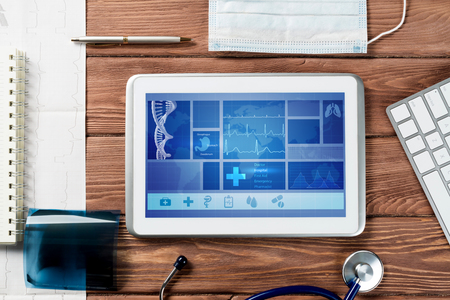 White tablet pc and doctor tools on wooden tableの写真素材