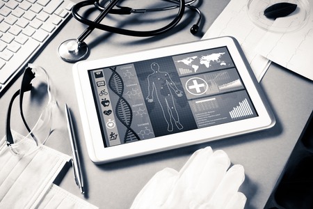 White tablet pc and doctor tools on gray surface