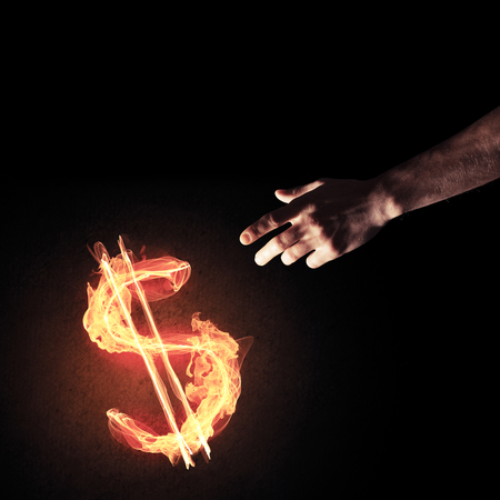 Close of man hands pointing at fire glowing dollar signの写真素材