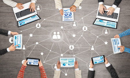 Group of people with devices in hands working together as symbol of networking and communicationの写真素材