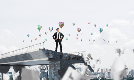 Confident businessman in suit standing among flying papers on broken bridge with flying balloons on background. 3D rendering.の写真素材