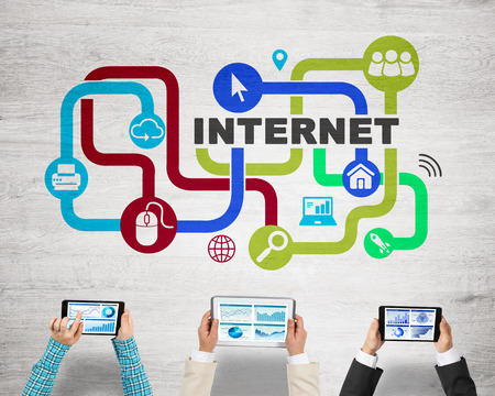 Group of three people with devices in hands working together as symbol of networking and communicationの写真素材