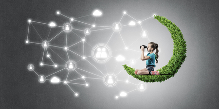 Cute kid girl sitting on green moon and social connection conceptの写真素材