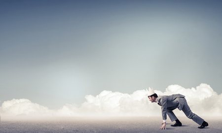 Young handsome businessman wearing white paper crown running in a hurryの写真素材