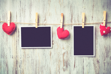 Instant photo frame and love hearts pinned to rope on wooden textured backgroundの写真素材