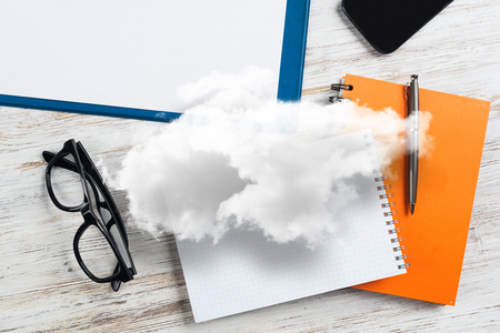 Top view of modern workplace with office stuff and cloud above presenting still office life. Mixed media.の写真素材