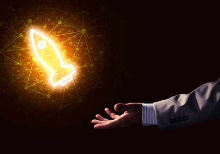Rocket glowing icon and businessman hand on dark backgroundの写真素材