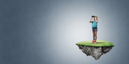 Cute kid girl sitting on floating island against concrete backgroundの写真素材