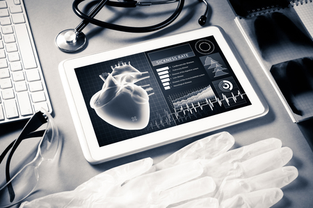 White tablet pc and doctor tools on gray surfaceの写真素材