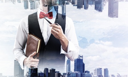 Double exposure of confident and young businessman in smart-casual wear smoking pipe and two modern urban worlds on background. Concept of young and successful entrepreneur.の写真素材