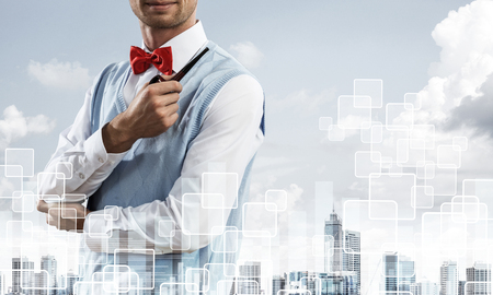 Double exposure of confident and young businessman in smart-casual wear smoking pipe and modern cityscape with business and media interface. Concept of new technologies for modern business.の写真素材