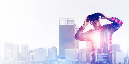 Young man with virtual reality headset or 3d glasses over cityscape backgroundの写真素材