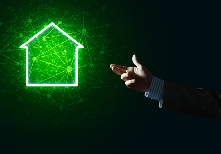 Hand of businessman touching with finger glowing home icon or symbolの写真素材