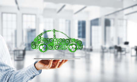 Car icon made of gears and cogwheels on white office background. Mixed media
