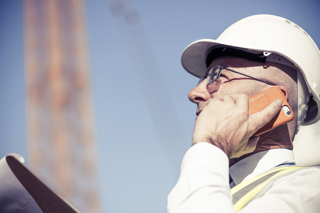 Senior engineer man in suit and helmet talking mobile phoneの写真素材