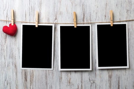 Instant photo frame and love hearts pinned to rope on wooden textured backgroundの写真素材