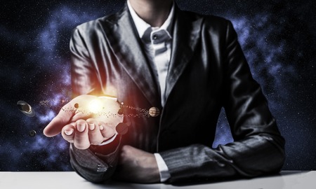 Businessman in suit presenting glowing solar system in his hands with dark cosmic background. 3D rendering.の写真素材