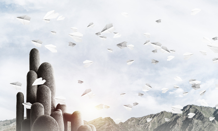 Image of high and huge stone columns located outdoors among flying paper planes with beautiful landscape on background. Wallpaper, backdrop with copyspace.の写真素材