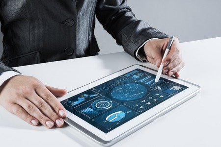 Close of businesswoman sitting at table and touching with stylus tablet pcの写真素材