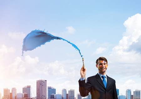 Successful businessman in black suit gesturing and smiling while standing with blue coloured splash against cityscape view on background.の写真素材