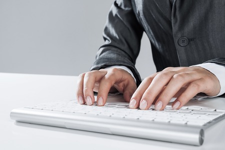 Close up of businessman hand typing on keyboard with mouse on wood tableの写真素材