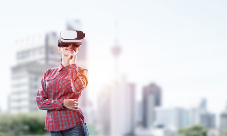 Young caucasian woman in virtual reality helmet against cityscape backgroundの写真素材