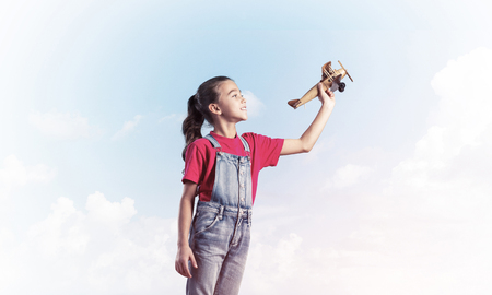 Cute kid girl in overalss with retro plane model in handの写真素材