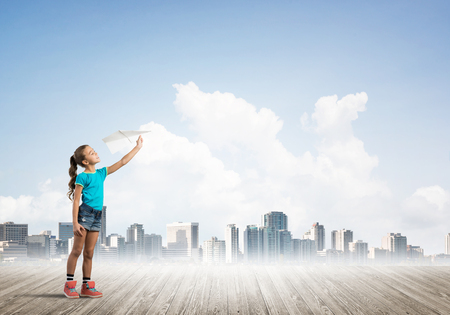 Cute kid girl standing on wooden floor with airplaneの写真素材