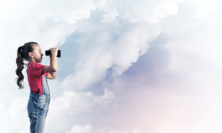 Little cute girl in overalls against sky background dreaming about futureの写真素材