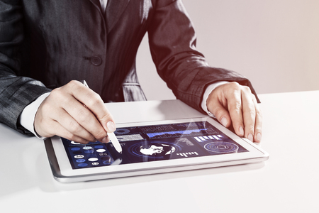 Close of businesswoman sitting at table and touching with stylus tablet pcの写真素材