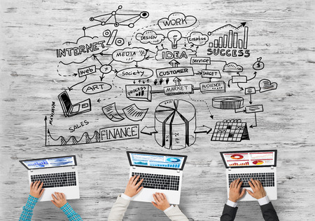 Group of three people with devices in hands working together as symbol of networking and communicationの写真素材