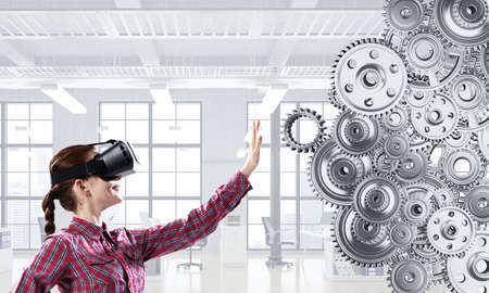 Young caucasian woman in virtual reality helmet touching gear mechanism. Mixed media