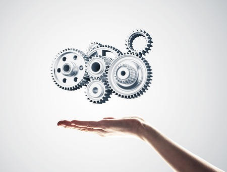 Close up of male hand holding metal gears mechanism in palmの写真素材