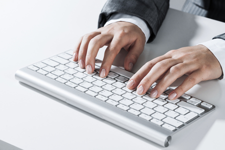 Close up of businesswoman hand typing on keyboard with mouse on wood tableの写真素材