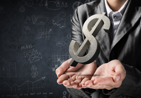 Cropped image of businessman in suit presenting gray concrete dollar sign in his hands. 3D rendering.の写真素材